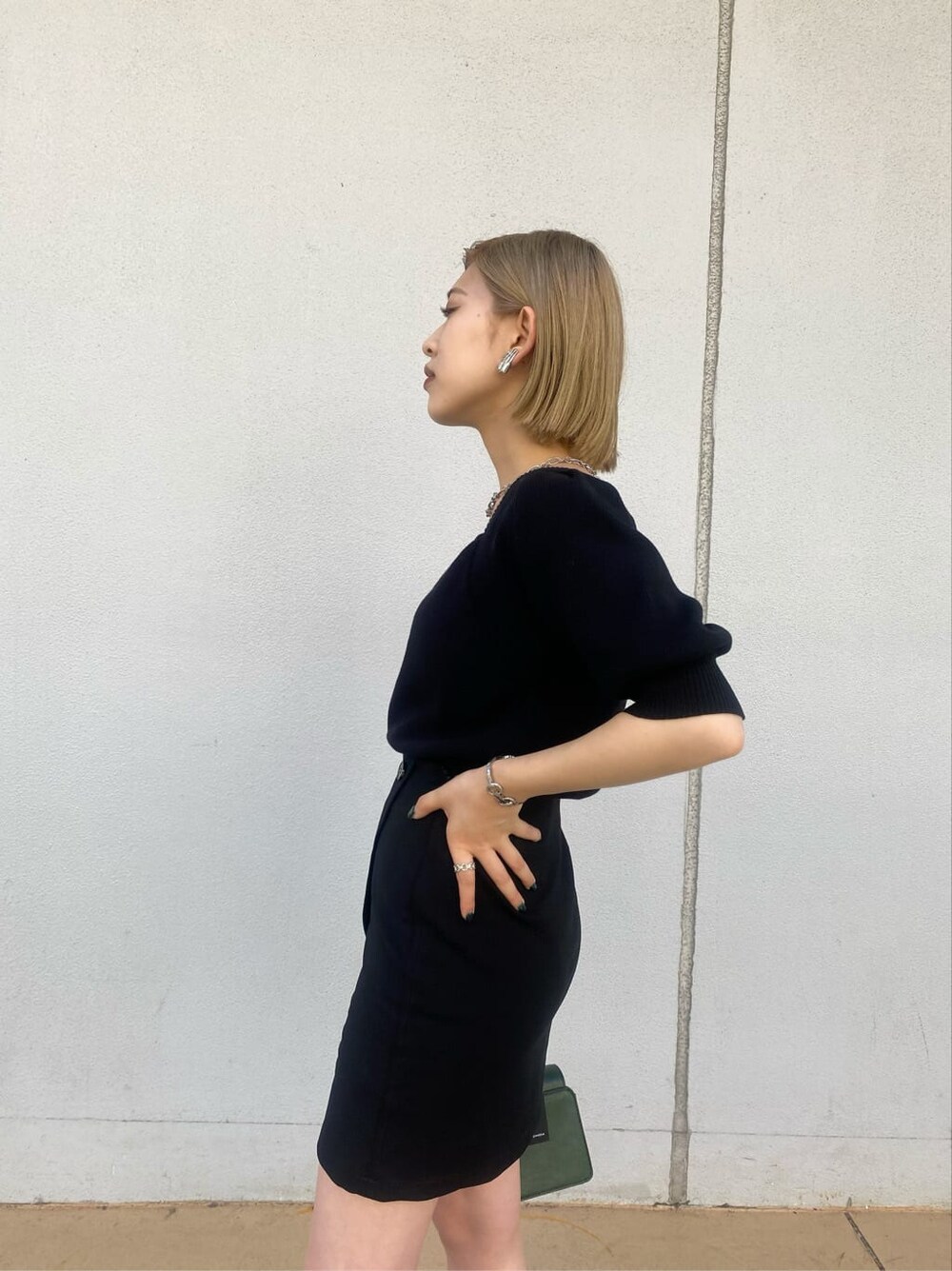 ベージュ系のトレンチコート、ブラック系のスカート、グリーン系のハンドバッグを着用したレディースの夏コーディネートの5枚目の写真