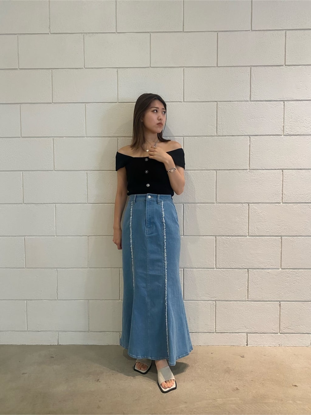 ブラウン系のハンドバッグ、ブルー系のスカート、ブラック系のタンクトップを着用したレディースの夏コーディネートの2枚目の写真