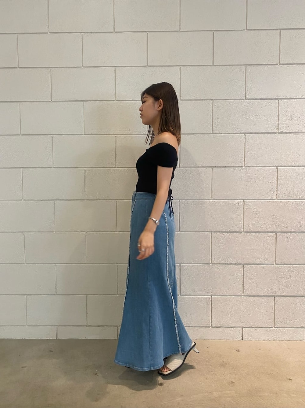 ブラウン系のハンドバッグ、ブルー系のスカート、ブラック系のタンクトップを着用したレディースの夏コーディネートの3枚目の写真