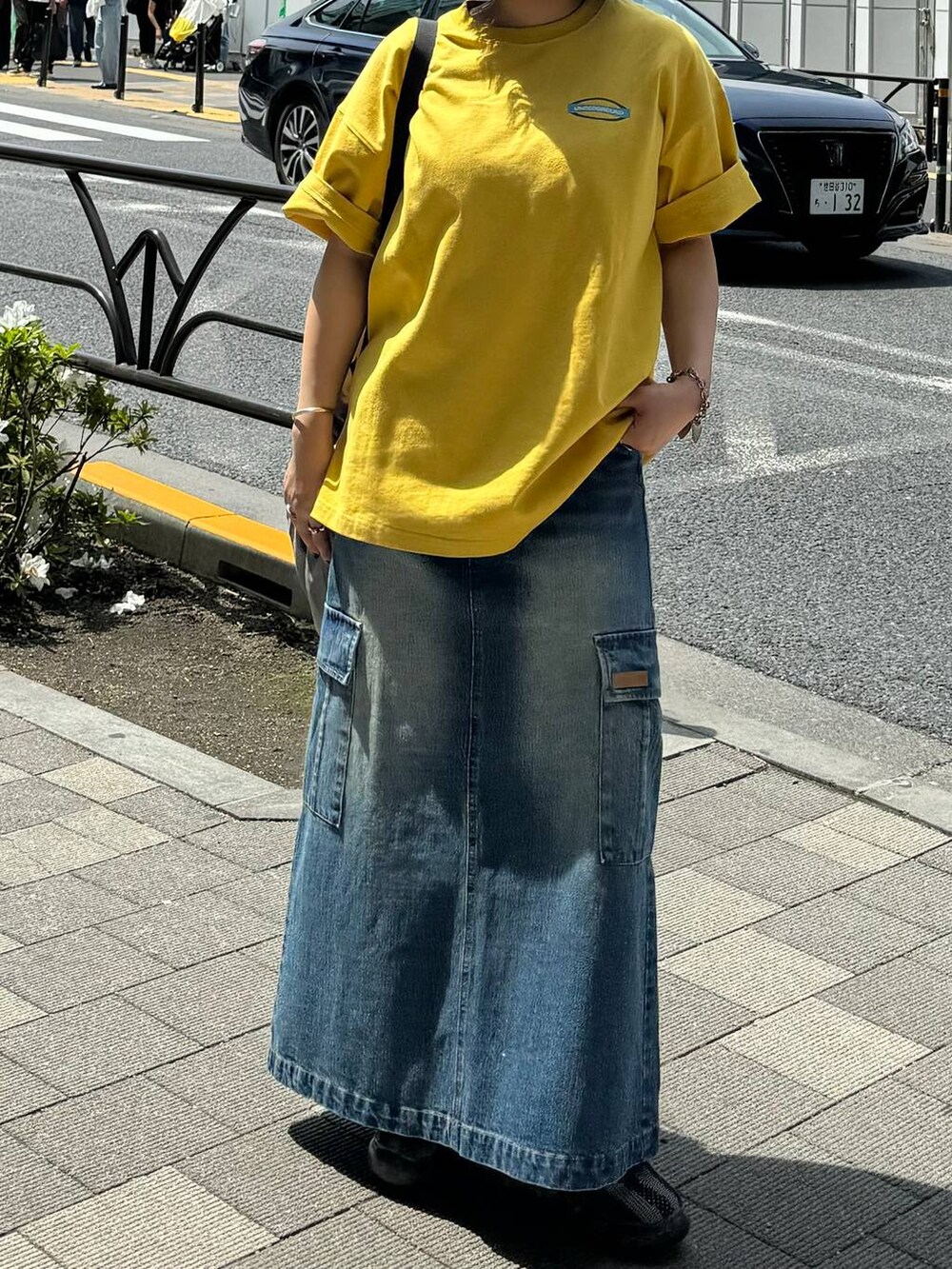 グレー系のバックパック/リュック、ブルー系のデニムスカート、イエロー系のTシャツ/カットソーを着用したレディースの春コーディネートの2枚目の写真