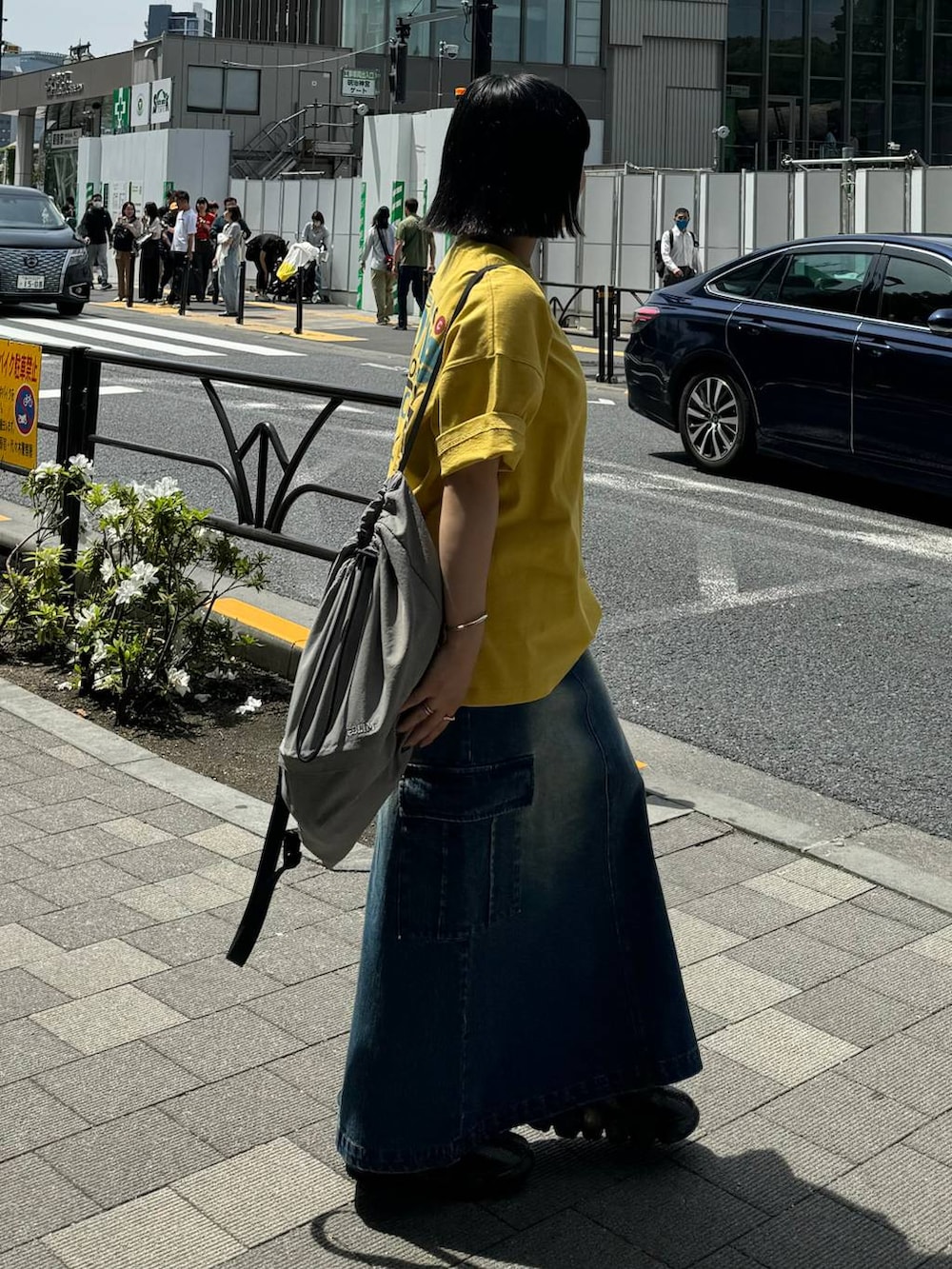 グレー系のバックパック/リュック、ブルー系のデニムスカート、イエロー系のTシャツ/カットソーを着用したレディースの春コーディネートの5枚目の写真