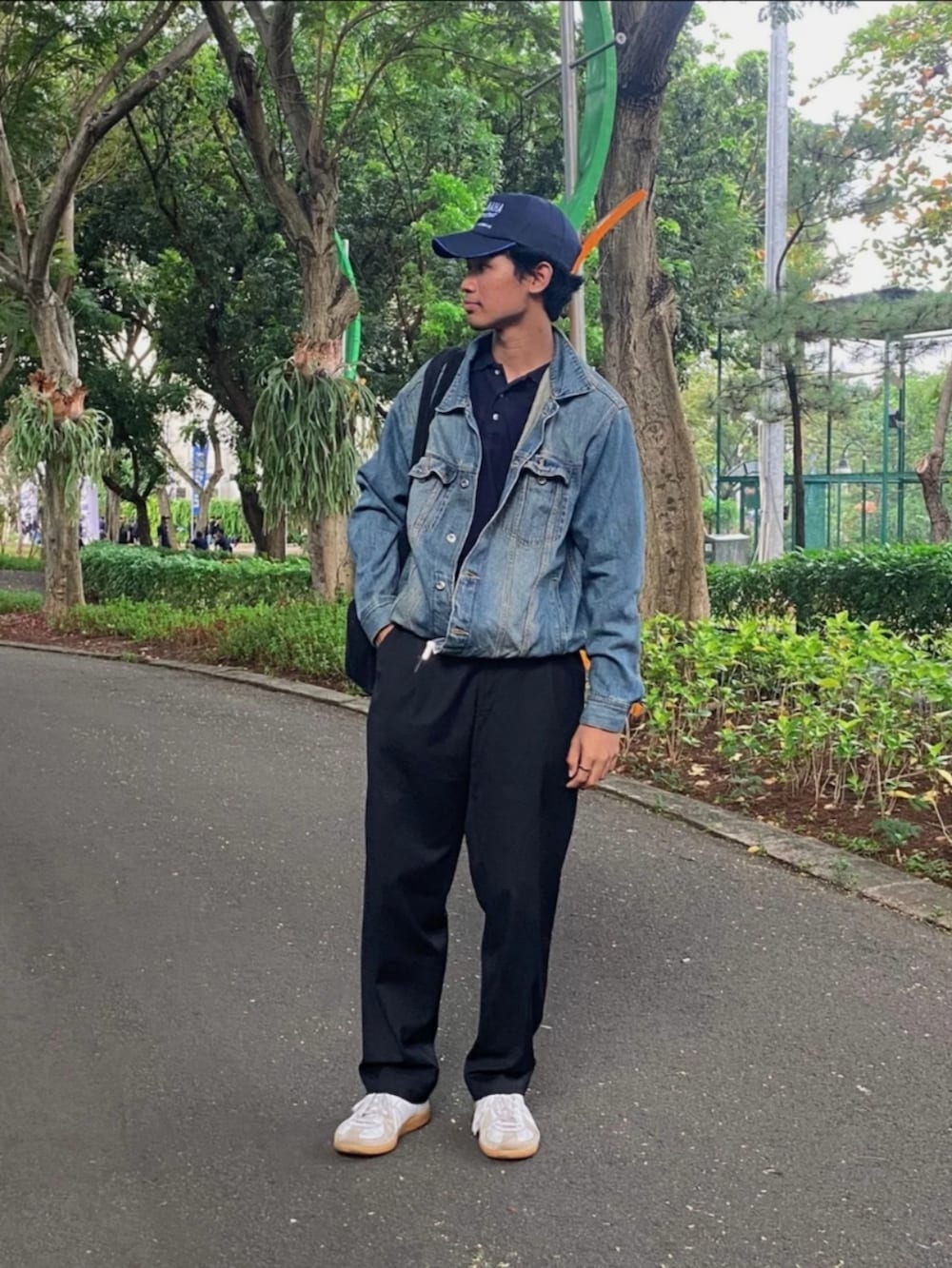 ホワイト系のスニーカー、ブラック系のスラックス、ブルー系のデニムジャケットを着用したメンズの夏コーディネートの2枚目の写真