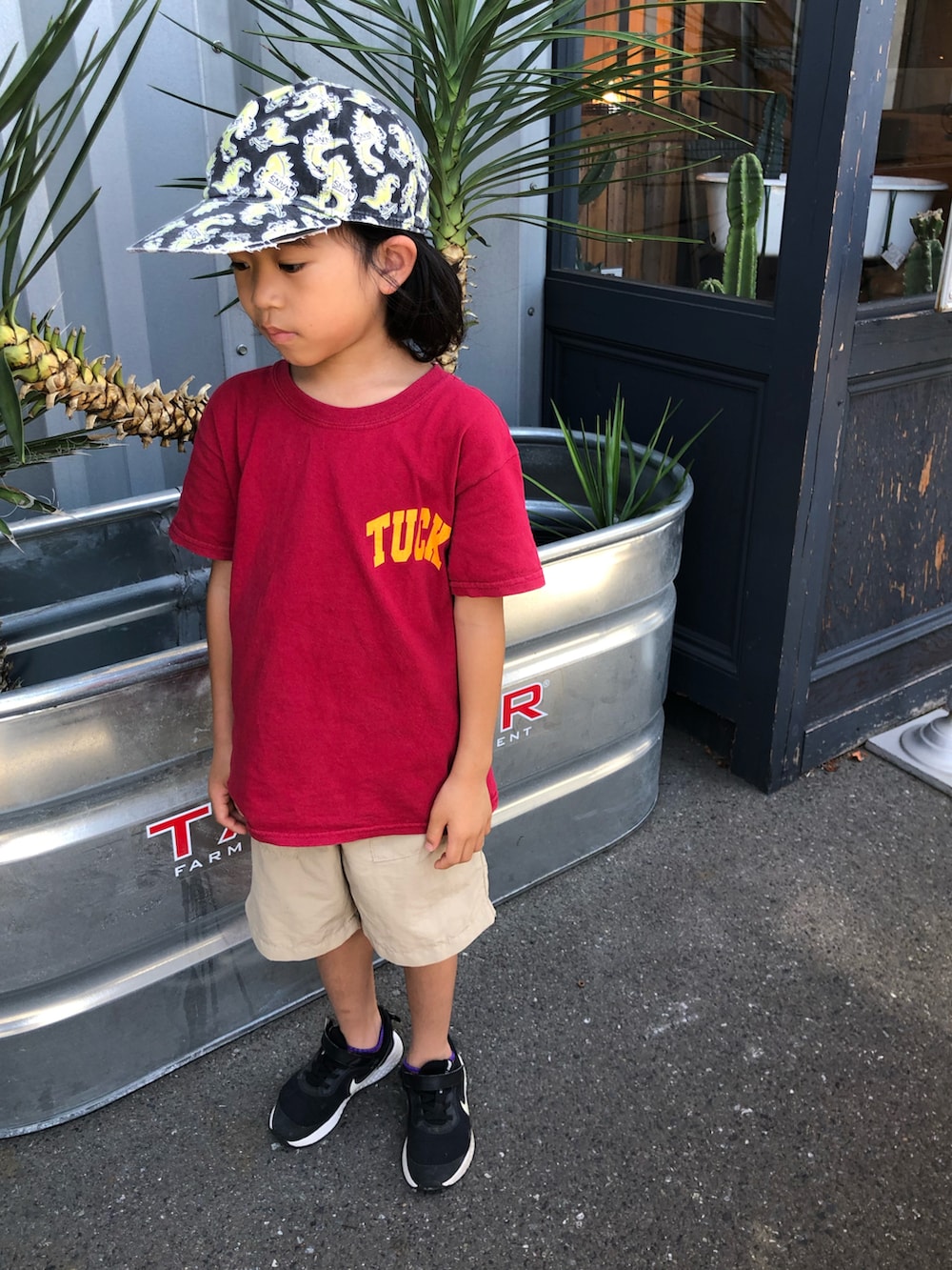 レッド系のTシャツ/カットソー、ブラック系のスニーカー、その他のキャップを着用したキッズの夏コーディネートの2枚目の写真