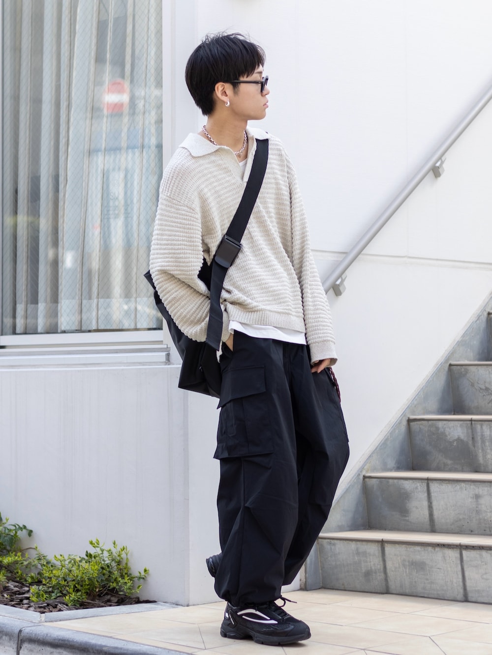 ブラック系のカーゴパンツ、ブラック系のスニーカー、ブラック系のメッセンジャーバッグを着用したメンズの春コーディネートの5枚目の写真