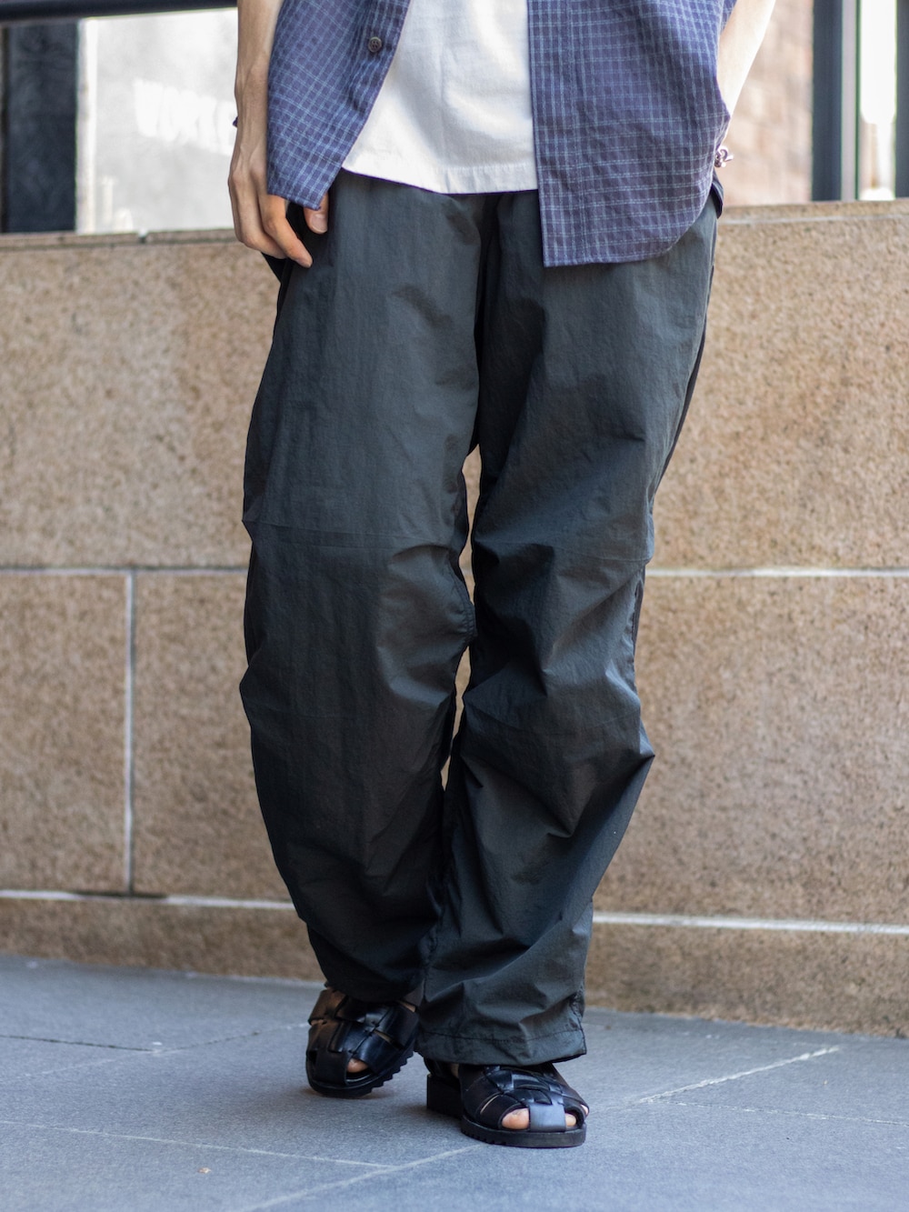 ブラック系のショルダーバッグ、ブラック系のサンダル、グレー系のパンツを着用したメンズの夏コーディネートの3枚目の写真