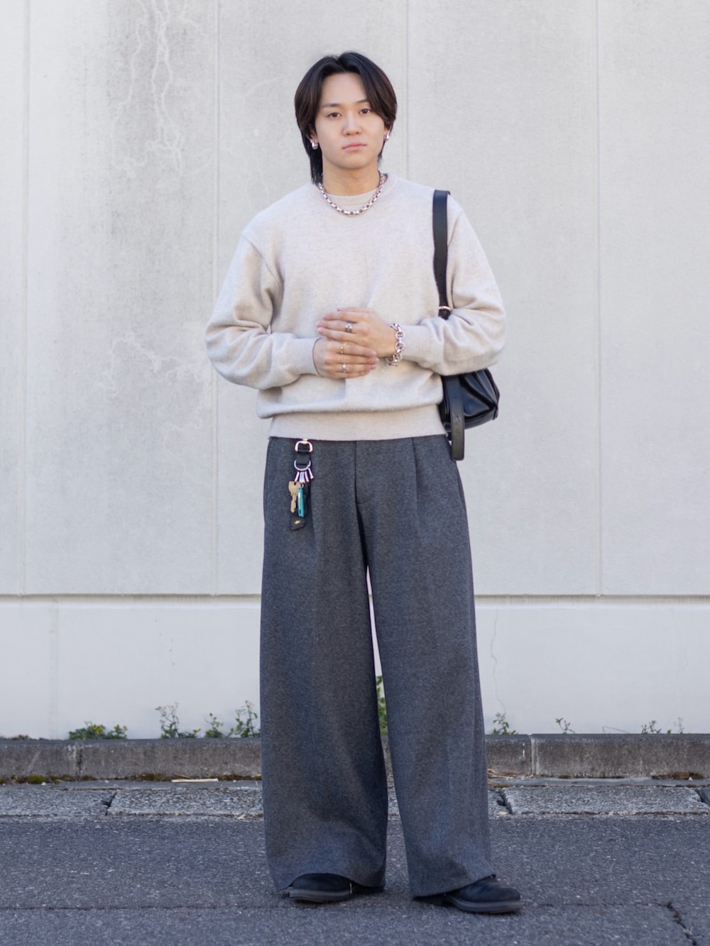 ホワイト系のニット/セーター、グレー系のスラックス、ブラック系のショルダーバッグを着用したメンズの春コーディネートの3枚目の写真