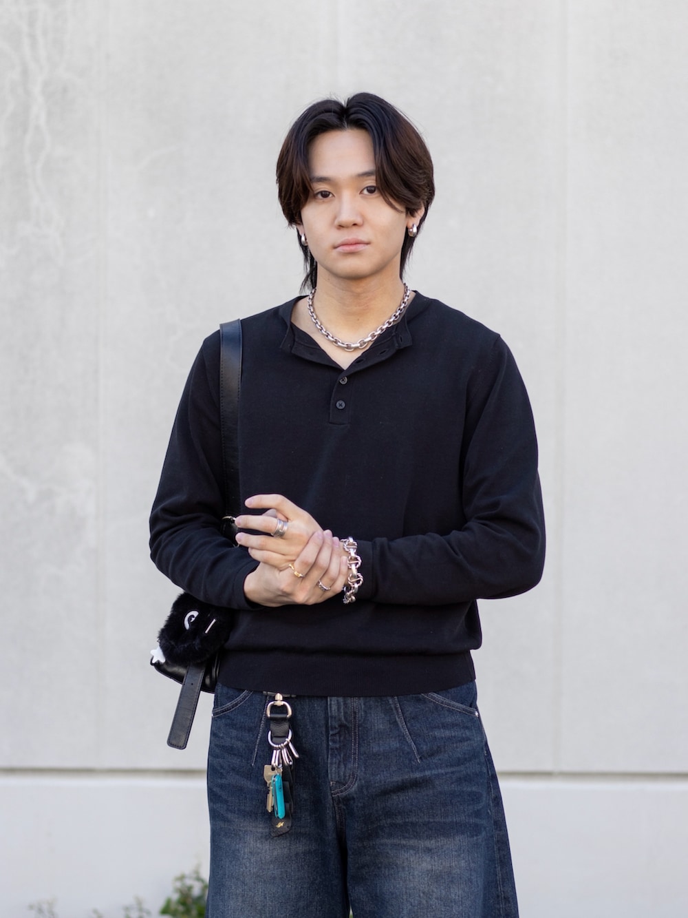 ブルー系のデニムパンツ、ブラック系のニット/セーター、ブラック系のドレスシューズを着用したメンズの春コーディネートの3枚目の写真