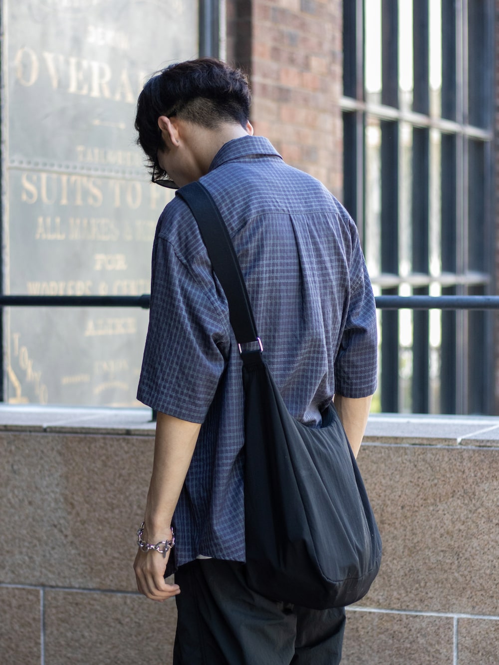 ブラック系のショルダーバッグ、ブラック系のサンダル、グレー系のパンツを着用したメンズの夏コーディネートの2枚目の写真