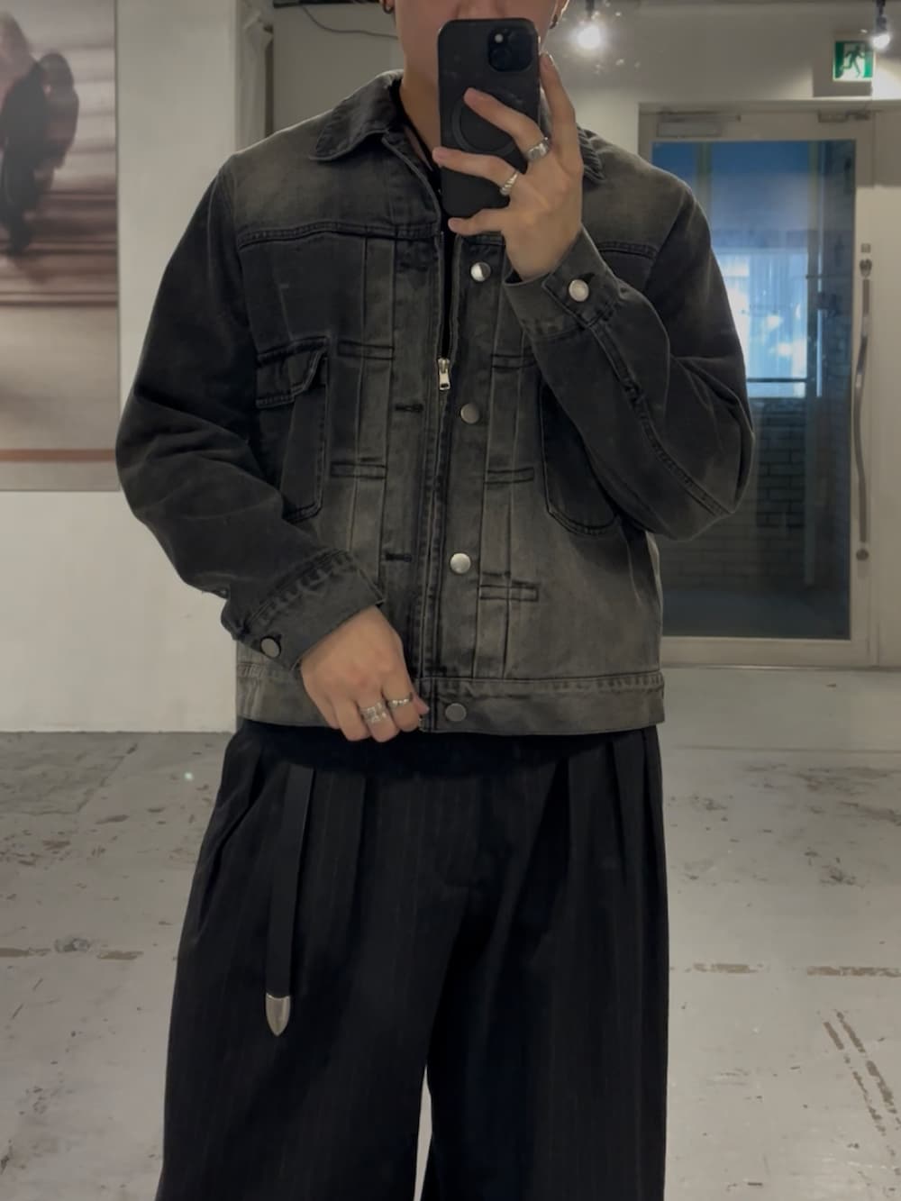 ブラック系のデニムジャケット、グレー系のスラックス、シルバー系のリングを着用したメンズの秋コーディネートの2枚目の写真