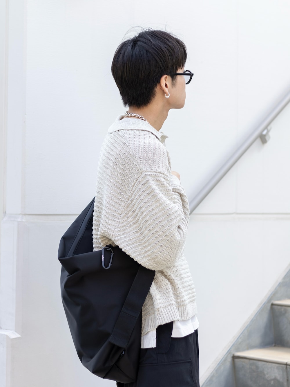 ブラック系のカーゴパンツ、ブラック系のスニーカー、ブラック系のメッセンジャーバッグを着用したメンズの春コーディネートの2枚目の写真