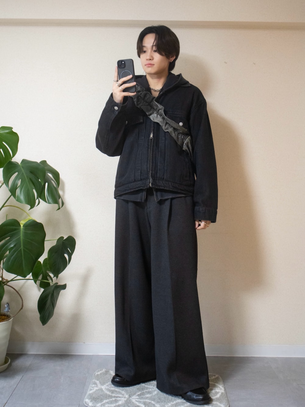 ブラック系のパーカー、ブラック系のデニムジャケット、グレー系のスラックスを着用したメンズの春コーディネートの2枚目の写真