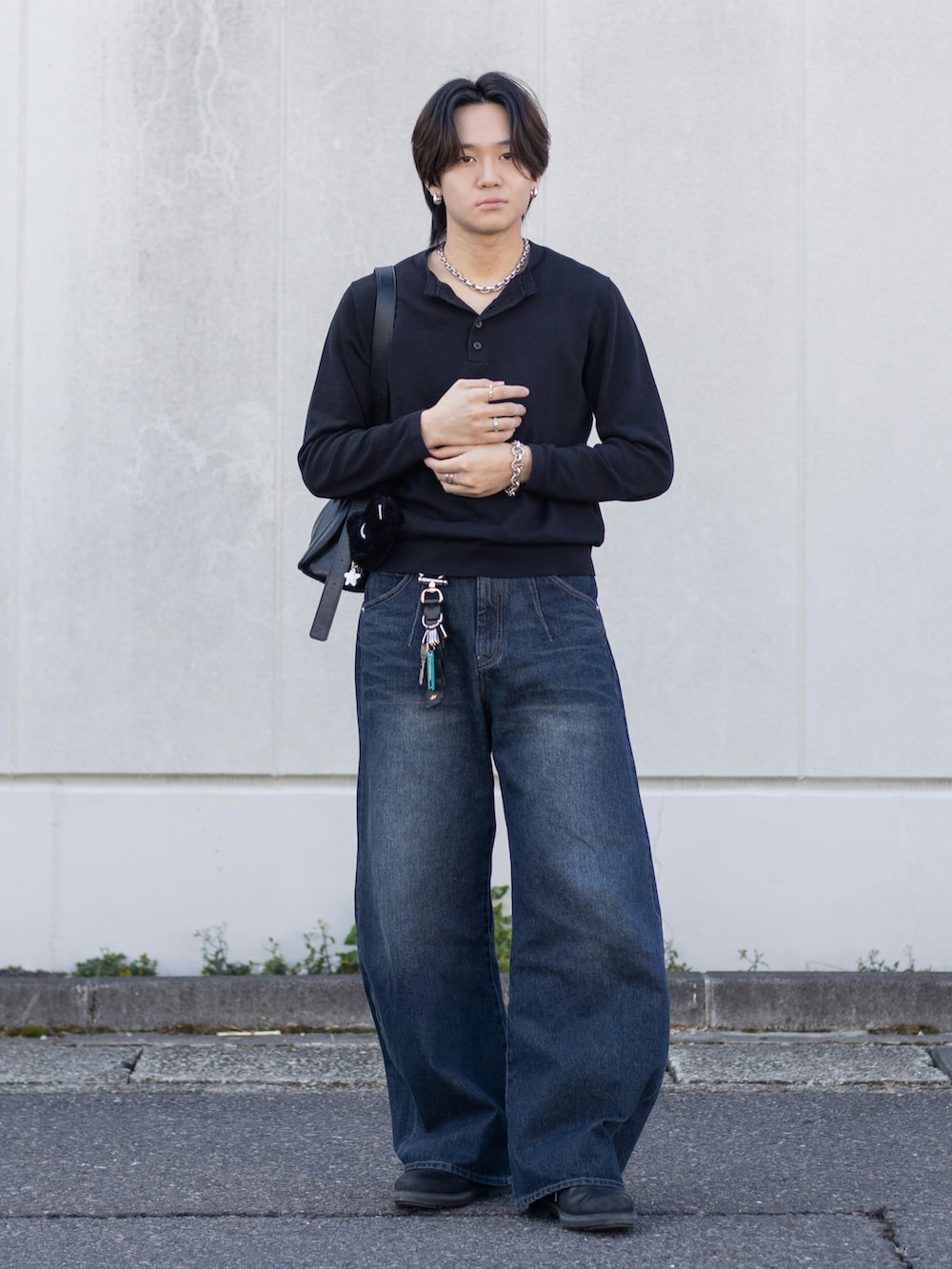 ブルー系のデニムパンツ、ブラック系のニット/セーター、ブラック系のドレスシューズを着用したメンズの春コーディネートの2枚目の写真