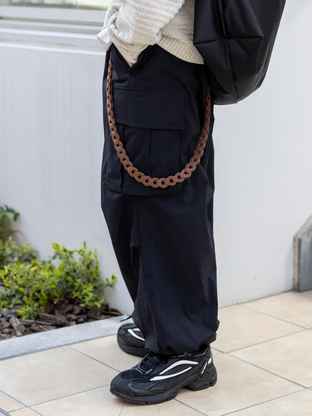 ブラック系のカーゴパンツ、ブラック系のスニーカー、ブラック系のメッセンジャーバッグを着用したメンズの春コーディネートの3枚目の写真