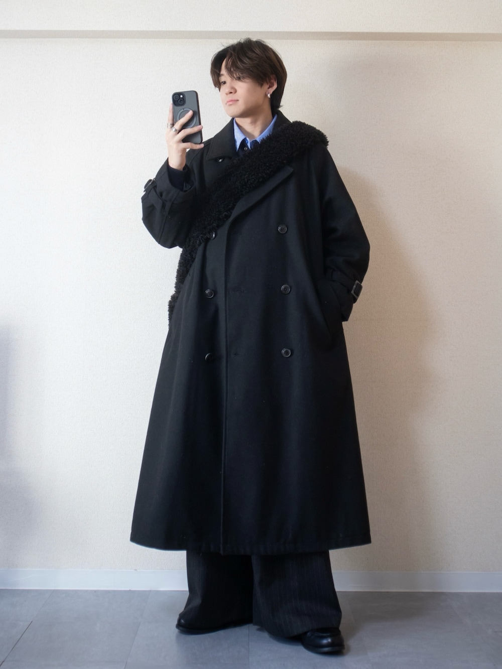ブルー系のニット/セーター、ブルー系のシャツ/ブラウス、ブラック系のステンカラーコートを着用したメンズの冬コーディネートの2枚目の写真