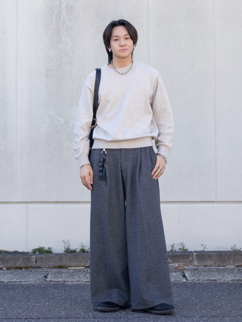 ホワイト系のニット/セーター、グレー系のスラックス、ブラック系のショルダーバッグを着用したメンズの春コーディネートの2枚目の写真