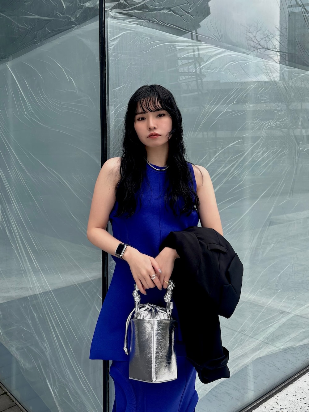 ブラック系のテーラードジャケット、ブルー系のニット/セーター、ブルー系のスカートを着用したレディースの春コーディネートの6枚目の写真