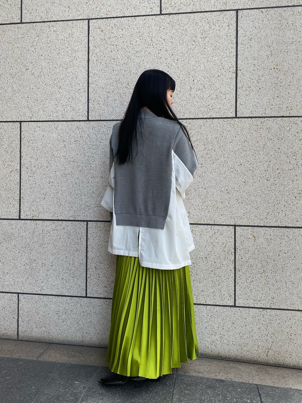 グレー系のニット/セーター、ブラック系のブーツ、グリーン系のスカートを着用したレディースの冬コーディネートの3枚目の写真