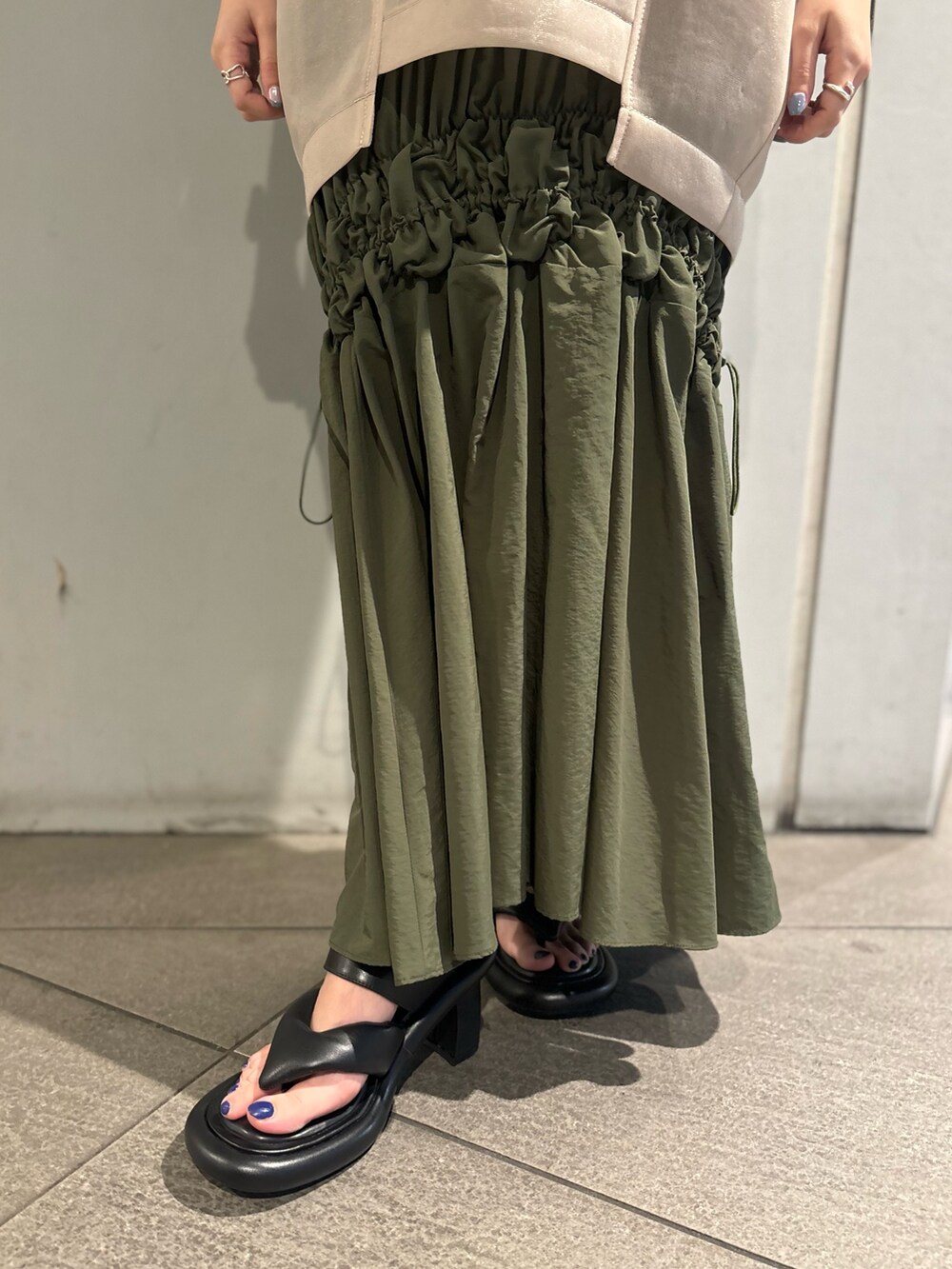 ベージュ系のTシャツ/カットソー、グリーン系のタンクトップ、グリーン系のスカートを着用したレディースの春コーディネートの6枚目の写真