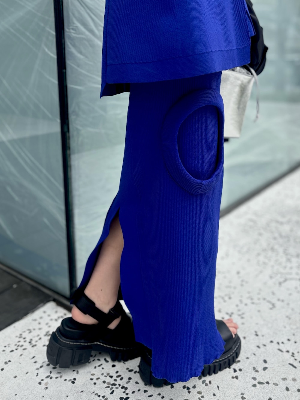 ブラック系のテーラードジャケット、ブルー系のニット/セーター、ブルー系のスカートを着用したレディースの春コーディネートの10枚目の写真