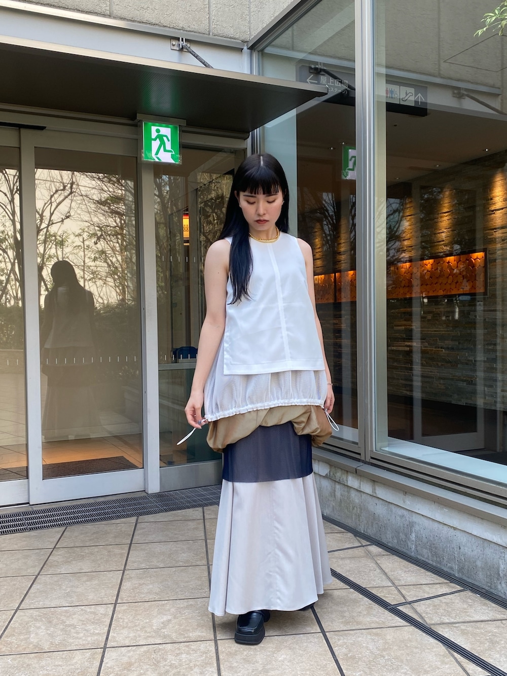 ホワイト系のタンクトップ、イエロー系のスカートを着用したレディースの春コーディネートの2枚目の写真