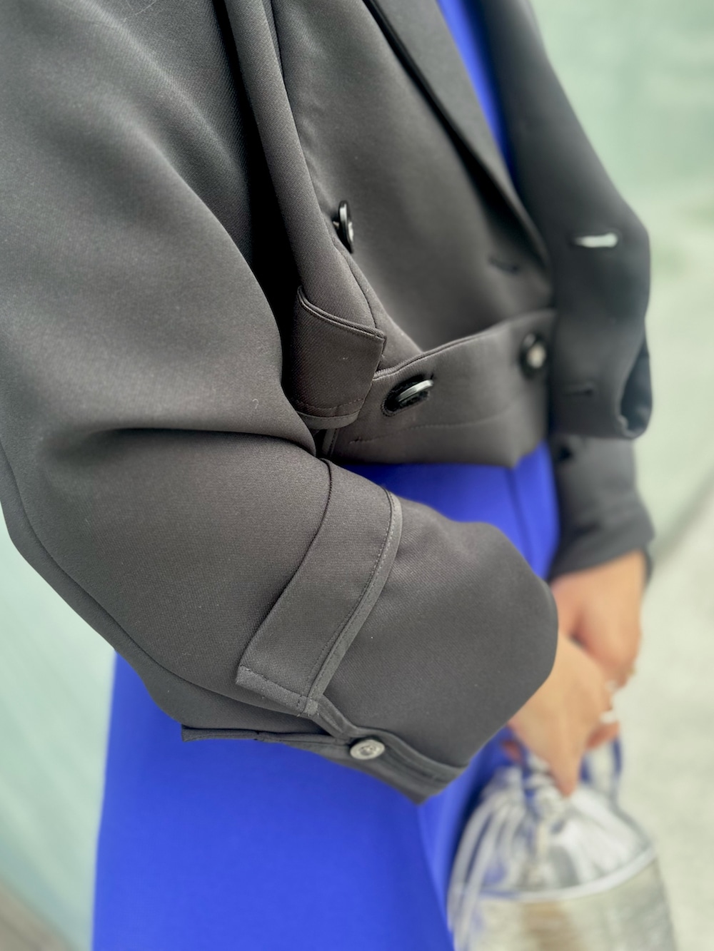 ブラック系のテーラードジャケット、ブルー系のニット/セーター、ブルー系のスカートを着用したレディースの春コーディネートの8枚目の写真