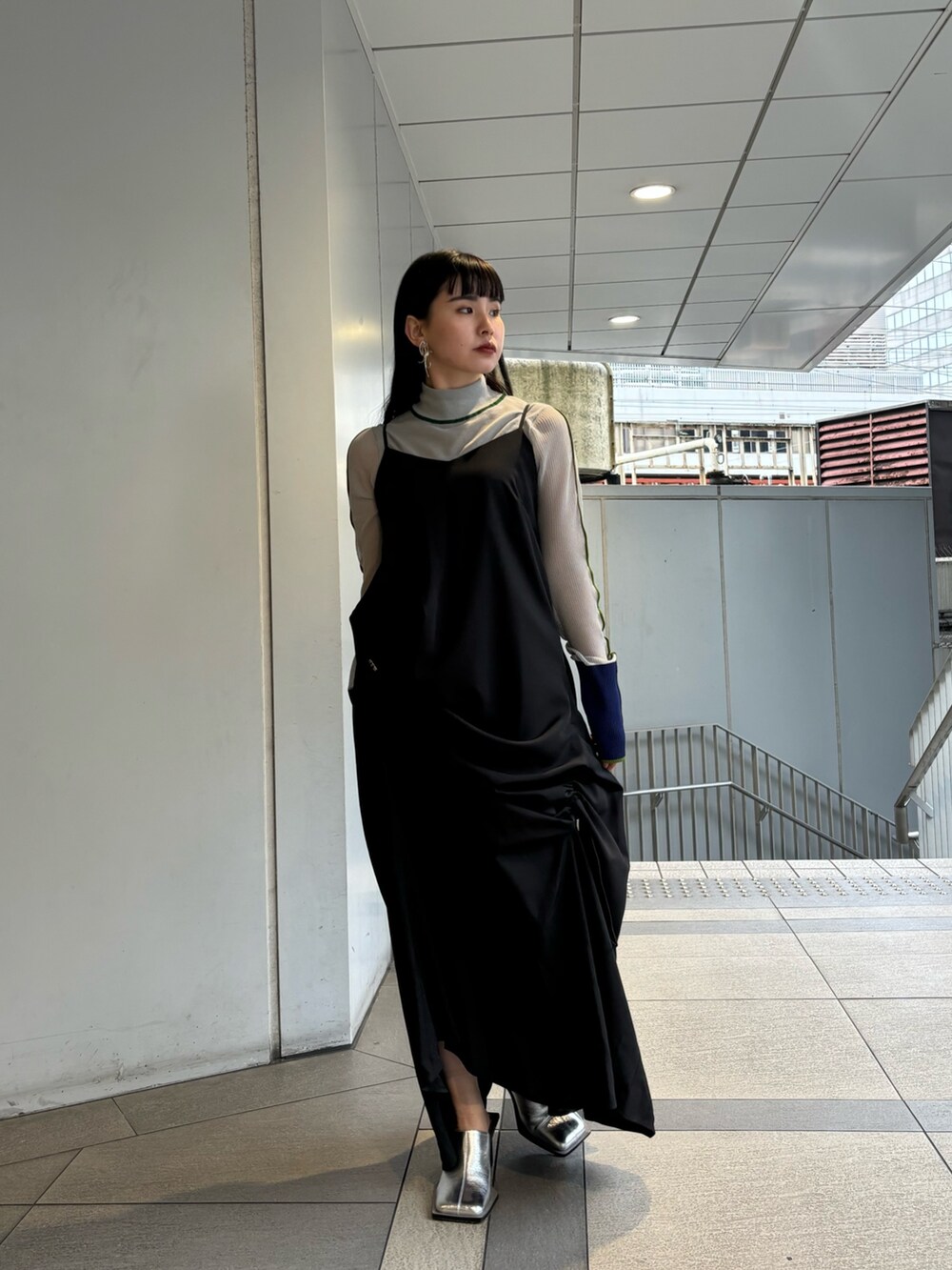 グレー系のニット/セーター、ブラック系のワンピース、シルバー系のパンプスを着用したレディースの春コーディネートの2枚目の写真