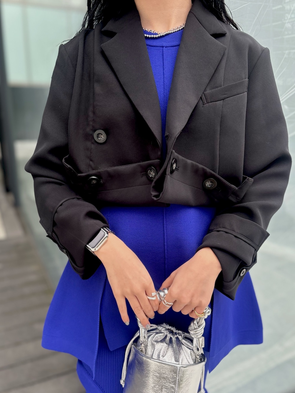 ブラック系のテーラードジャケット、ブルー系のニット/セーター、ブルー系のスカートを着用したレディースの春コーディネートの7枚目の写真