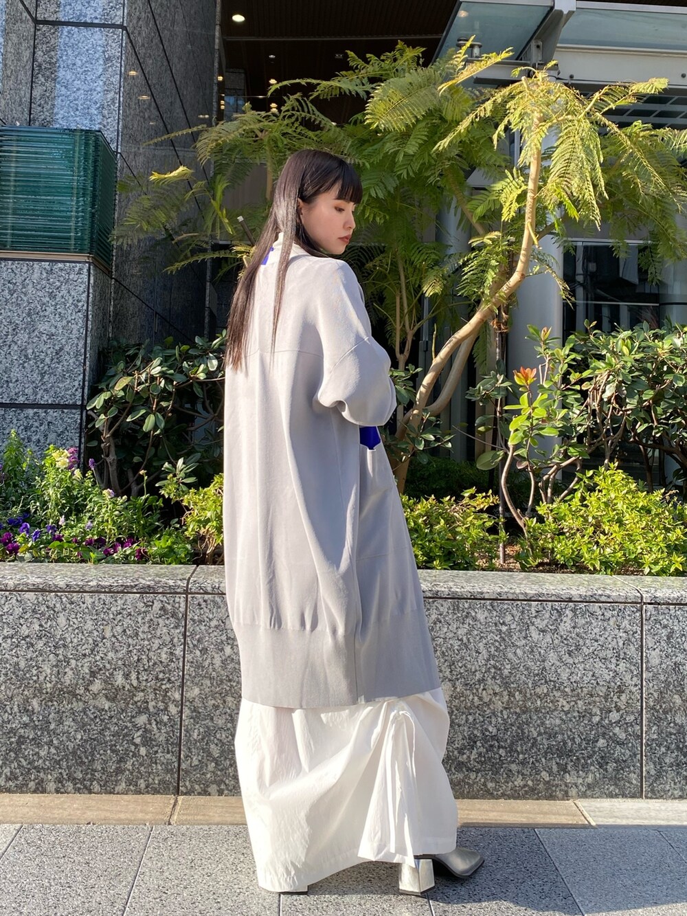 グレー系のニット/セーター、グレー系のカーディガン/ボレロ、ホワイト系のスカートを着用したレディースの冬コーディネートの4枚目の写真