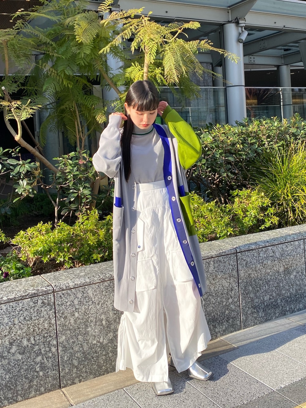 グレー系のニット/セーター、グレー系のカーディガン/ボレロ、ホワイト系のスカートを着用したレディースの冬コーディネートの2枚目の写真