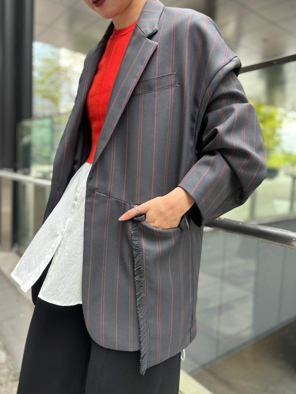 グレー系のテーラードジャケット、オレンジ系のニット/セーター、ホワイト系のシャツ/ブラウスを着用したレディースの夏コーディネートの7枚目の写真