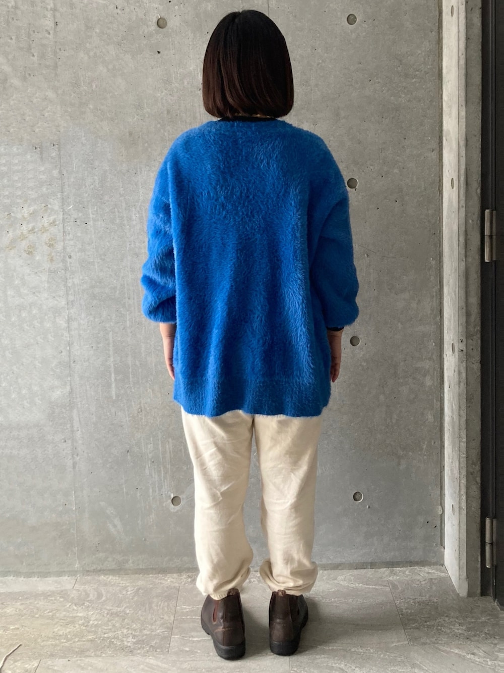 ブルー系のカーディガン/ボレロ、ベージュ系のその他パンツ、ブラウン系のブーツを着用したレディースの冬コーディネートの2枚目の写真