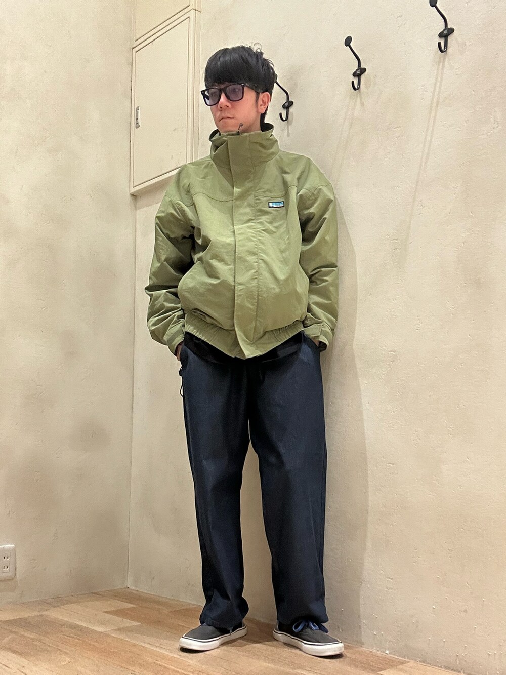 グリーン系のナイロンジャケット、ブルー系のパンツ、ブラック系のシューズを着用したメンズの秋コーディネートの2枚目の写真