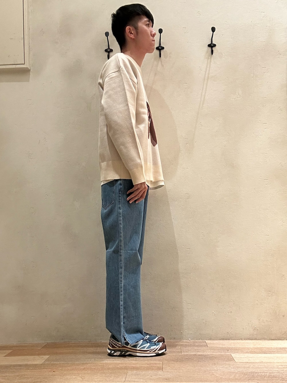 ブルー系のデニムパンツ、ホワイト系のニット/セーター、ブルー系のスニーカーを着用したメンズの秋コーディネートの2枚目の写真