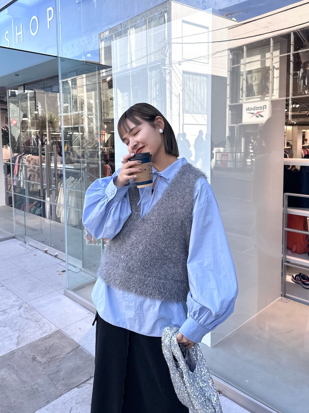 グレー系のベスト、ブルー系のシャツ/ブラウス、ブラック系のスカートを着用したレディースの冬コーディネートの2枚目の写真