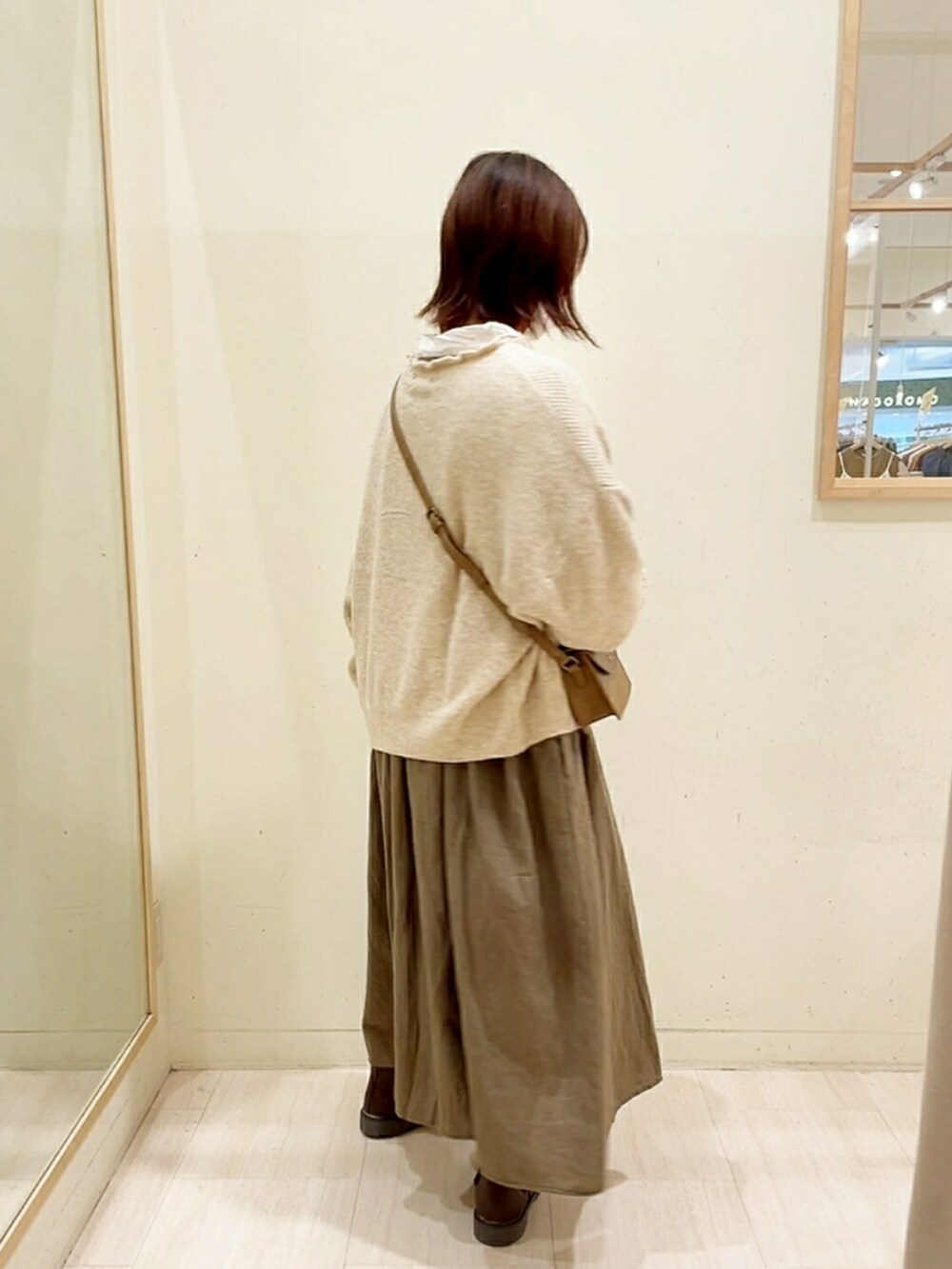 ベージュ系のカーディガン/ボレロ、ホワイト系のシャツ/ブラウス、グリーン系のワンピースを着用したレディースの秋コーディネートの3枚目の写真