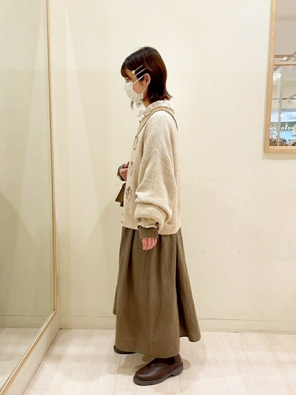 ベージュ系のカーディガン/ボレロ、ホワイト系のシャツ/ブラウス、グリーン系のワンピースを着用したレディースの秋コーディネートの2枚目の写真