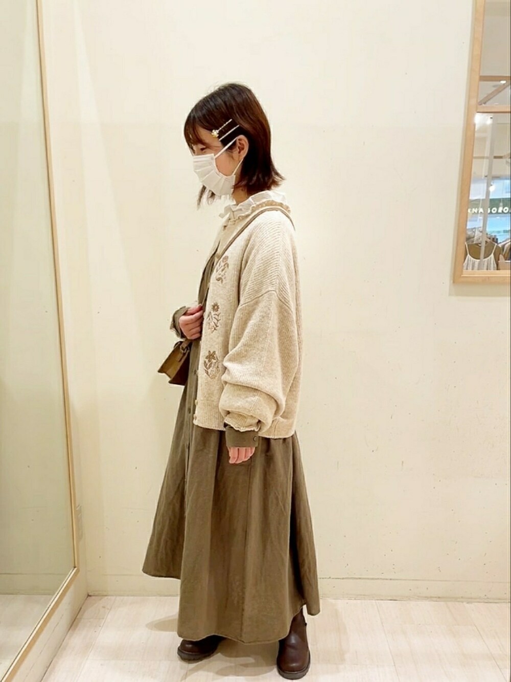 ベージュ系のカーディガン/ボレロ、ホワイト系のシャツ/ブラウス、グリーン系のワンピースを着用したレディースの秋コーディネートの4枚目の写真