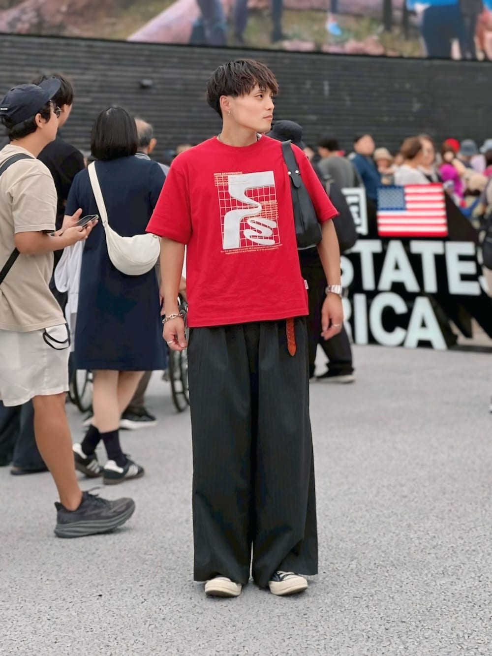 レッド系のTシャツ/カットソー、グレー系のスラックス、シルバー系のリングを着用したメンズの秋コーディネートの2枚目の写真