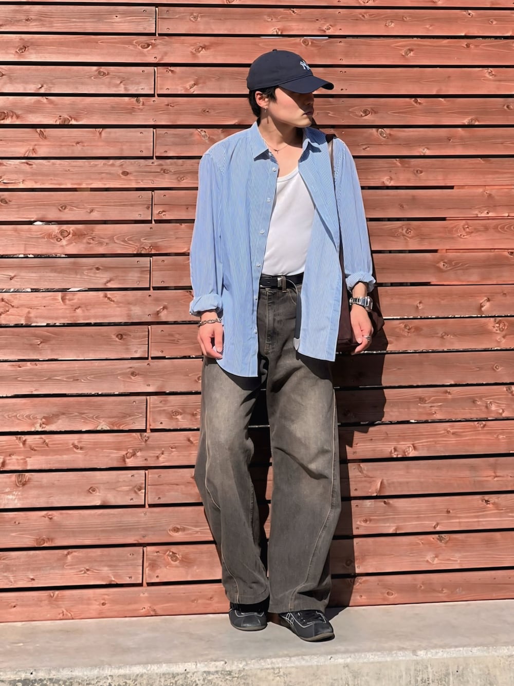 ホワイト系のタンクトップ、ブラック系のデニムパンツ、ブラウン系のショルダーバッグを着用したメンズの春コーディネートの2枚目の写真