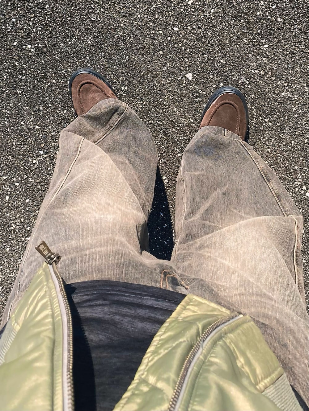 ブラック系のデニムパンツ、ブラック系のハンドバッグ、ブラウン系のスニーカーを着用したメンズの冬コーディネートの3枚目の写真