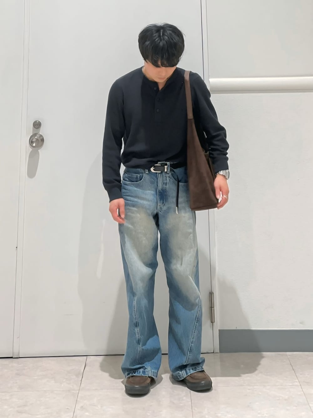 ブルー系のデニムパンツ、ブラウン系のショルダーバッグ、ブラウン系のスニーカーを着用したメンズの春コーディネートの3枚目の写真