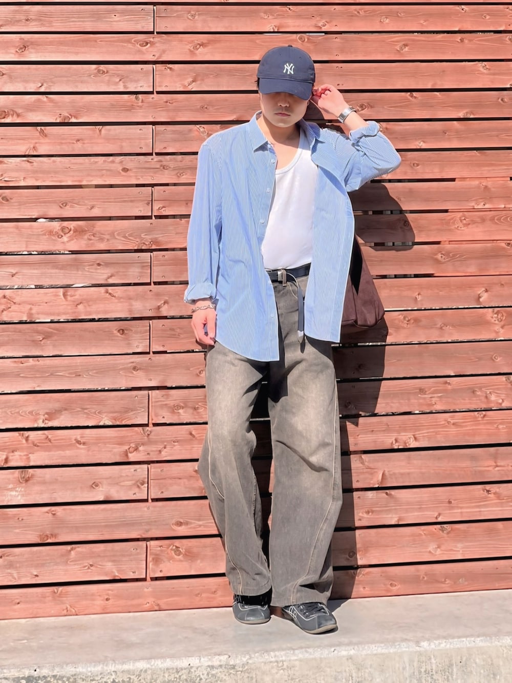 ホワイト系のタンクトップ、ブラック系のデニムパンツ、ブラウン系のショルダーバッグを着用したメンズの春コーディネートの3枚目の写真