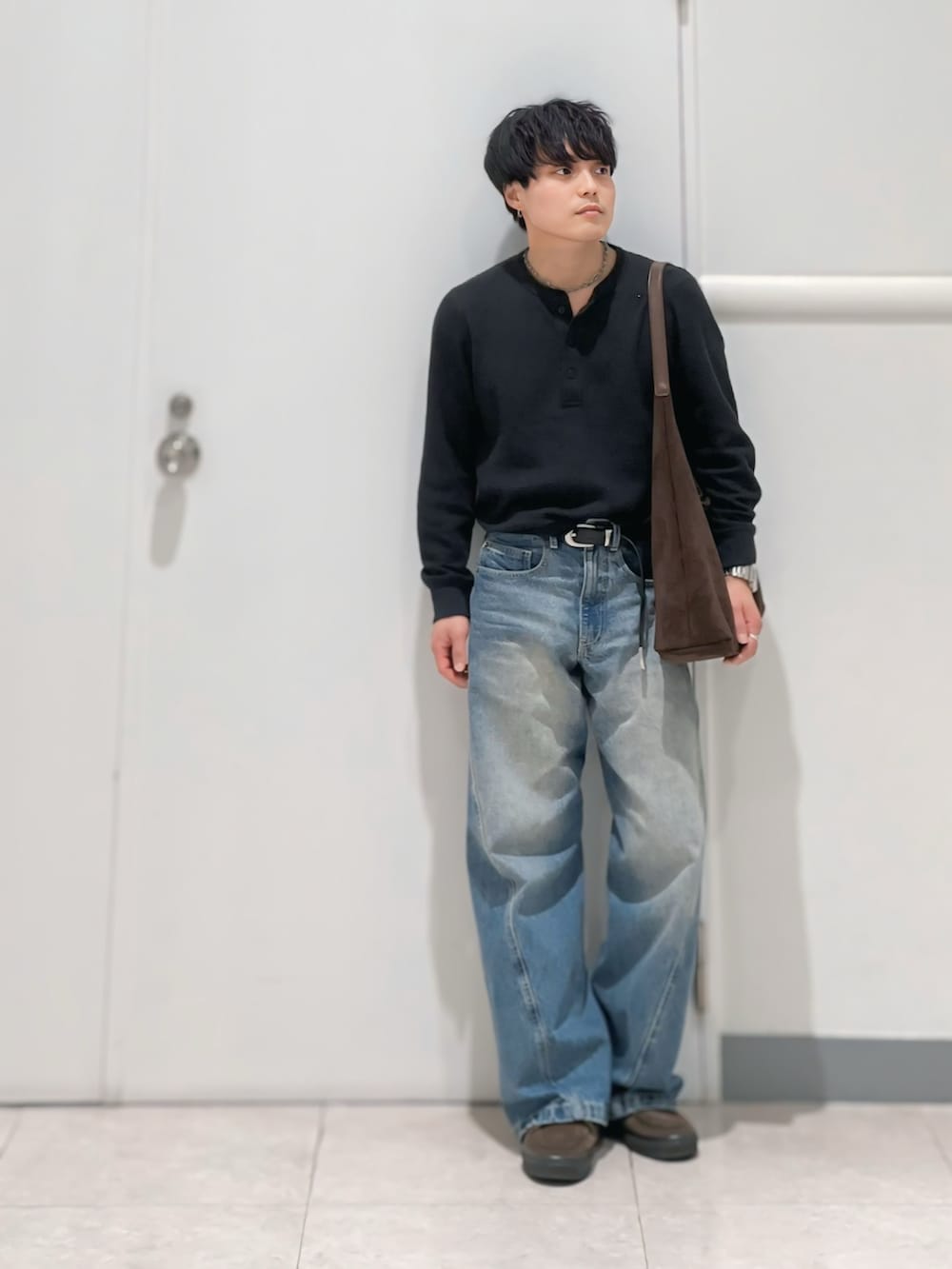 ブルー系のデニムパンツ、ブラウン系のショルダーバッグ、ブラウン系のスニーカーを着用したメンズの春コーディネートの2枚目の写真