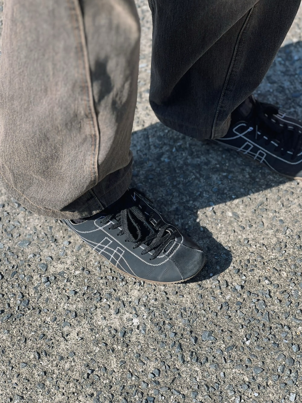 ホワイト系のタンクトップ、ブラック系のデニムパンツ、ブラウン系のショルダーバッグを着用したメンズの春コーディネートの4枚目の写真