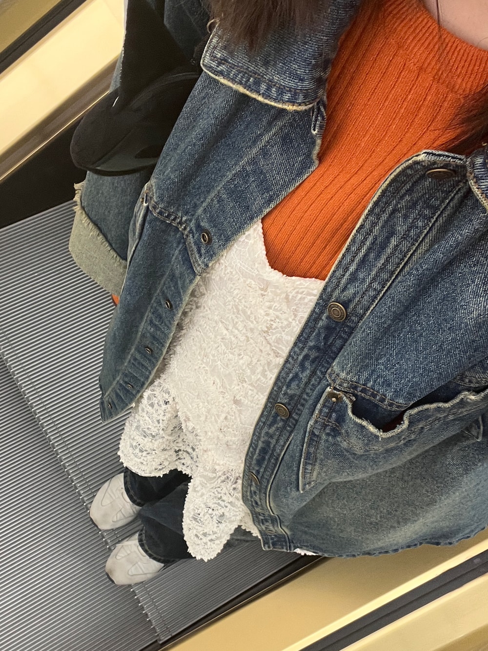 オレンジ系のニット/セーター、ホワイト系のチュニック、ブルー系のシャツ/ブラウスを着用したレディースの冬コーディネートの2枚目の写真