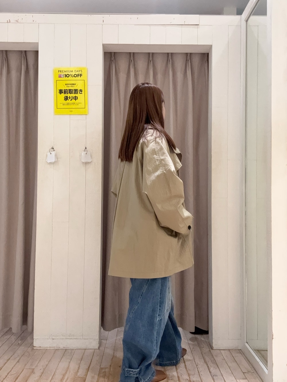 ベージュ系のトレンチコート、ホワイト系のカーディガン/ボレロ、ブルー系のデニムパンツを着用したレディースの春コーディネートの3枚目の写真