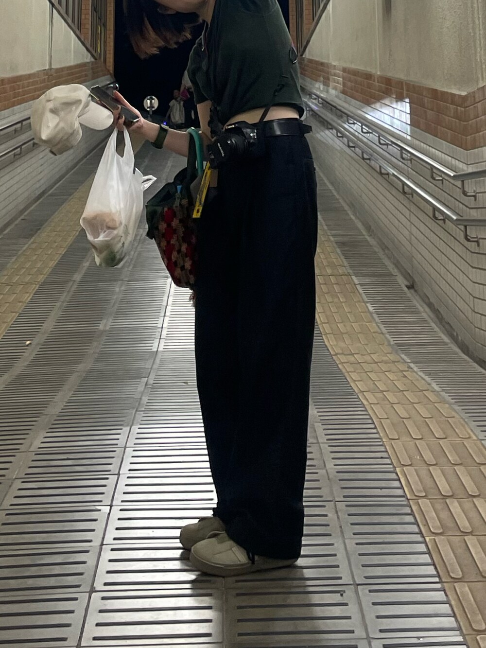 ブラック系のチノパンツ、グリーン系のスニーカー、ベージュ系のキャップを着用したレディースの夏コーディネートの2枚目の写真