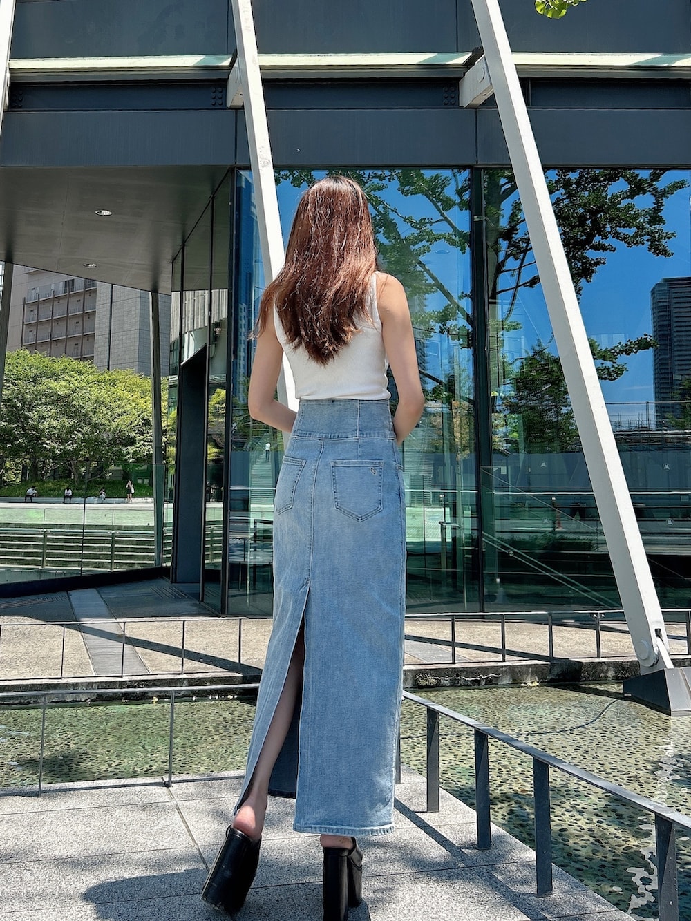 ホワイト系のニット/セーター、ブルー系のデニムスカート、ブラック系のサンダルを着用したレディースの夏コーディネートの2枚目の写真