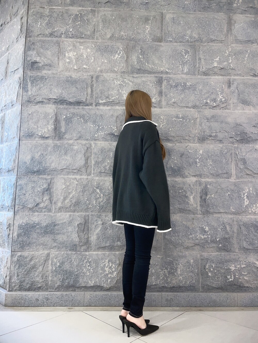 ホワイト系のニット/セーター、ブラック系のデニムパンツ、ホワイト系のパンプスを着用したレディースの冬コーディネートの4枚目の写真