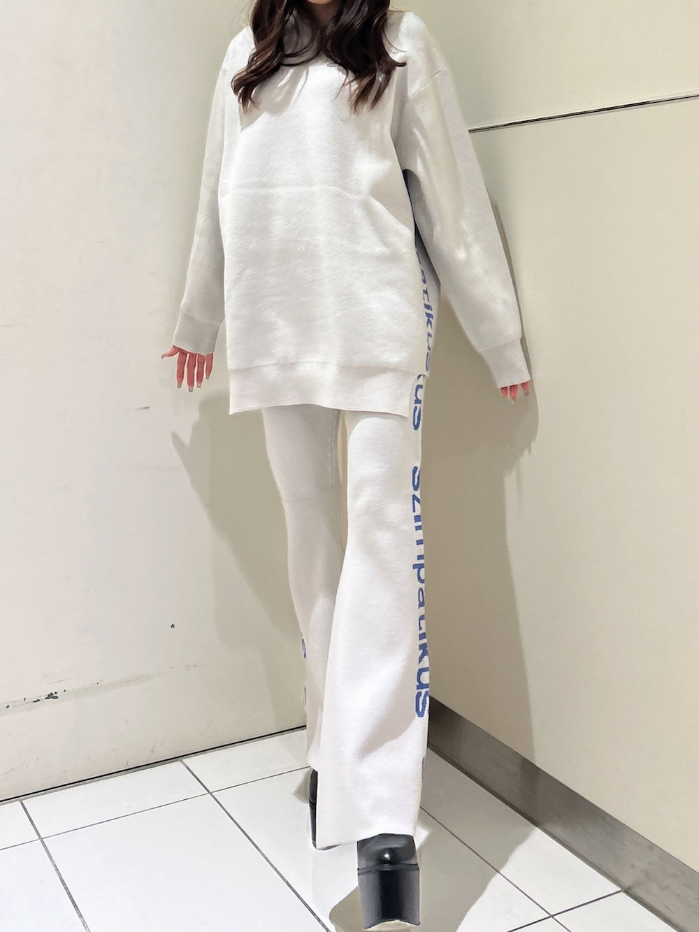 ホワイト系のニット/セーター、オレンジ系のその他パンツ、ブラック系のブーツを着用したレディースの冬コーディネートの3枚目の写真
